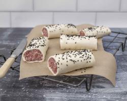 Raw pork sausage rolls on top of wire baking rack